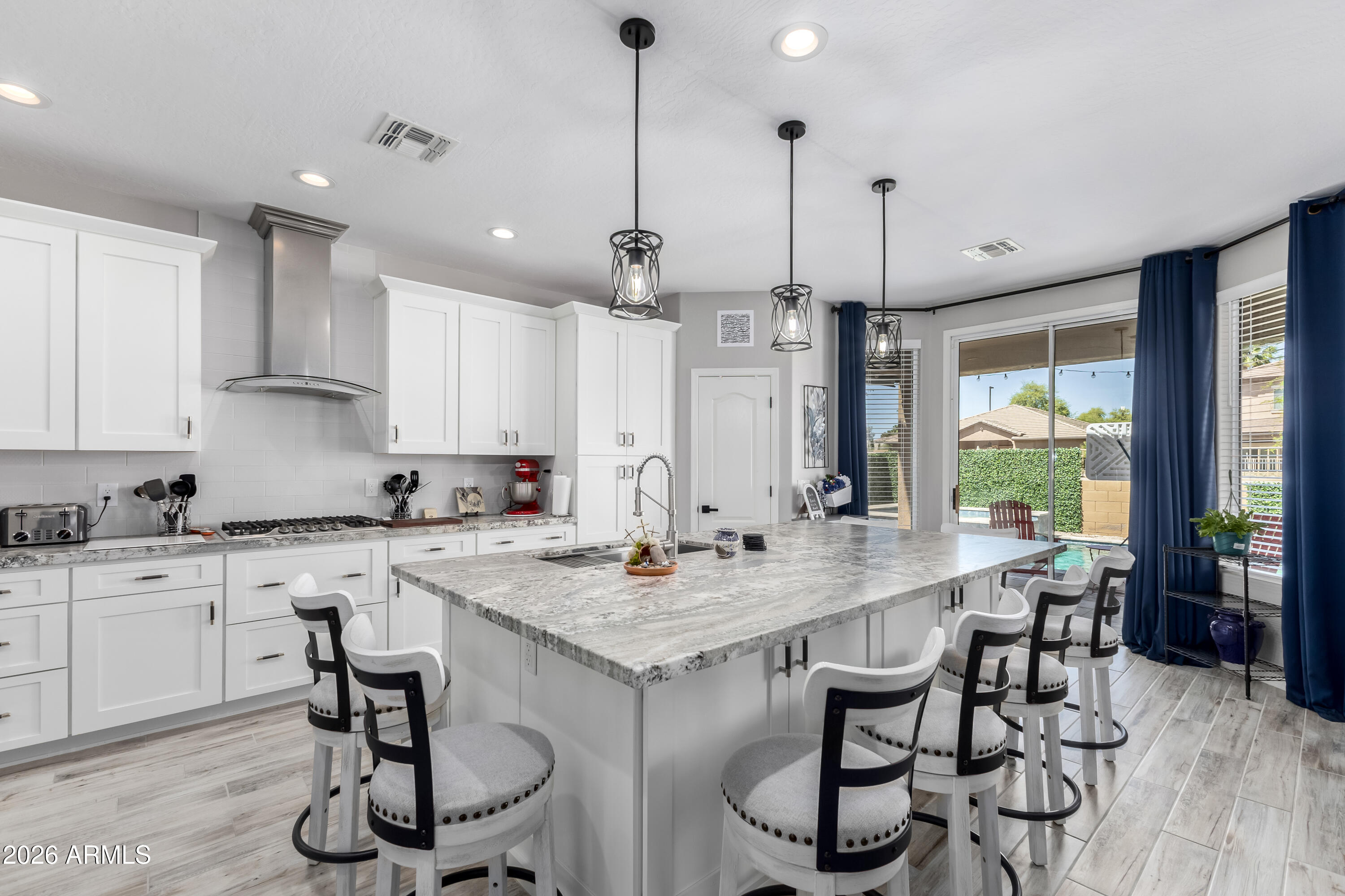 3256 East Geronimo Court Gilbert, AZ 85295 - Photo 28 of 53 a kitchen with stainless steel appliances granite countertop a stove a refrigerator a sink a dining table and chairs with wooden floor