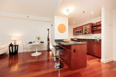 a living room with kitchen island and a wooden floor