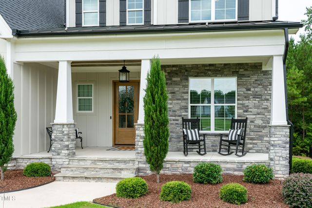 a view of a patio with table and chairs potted plants and floor to ceiling window