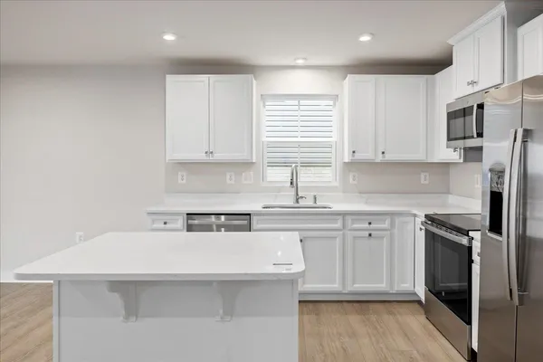 a kitchen with stainless steel appliances granite countertop a sink a stove a refrigerator and cabinets