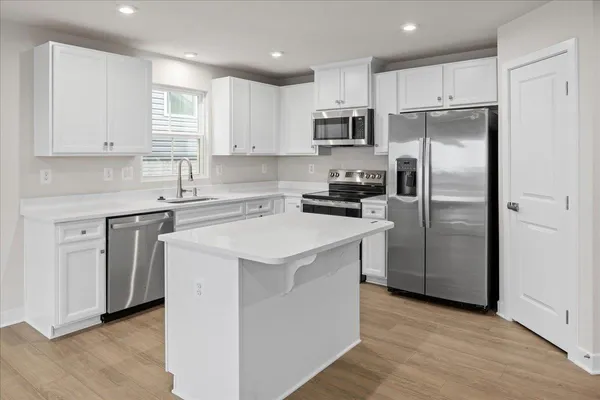 a kitchen with white cabinets stainless steel appliances and a refrigerator