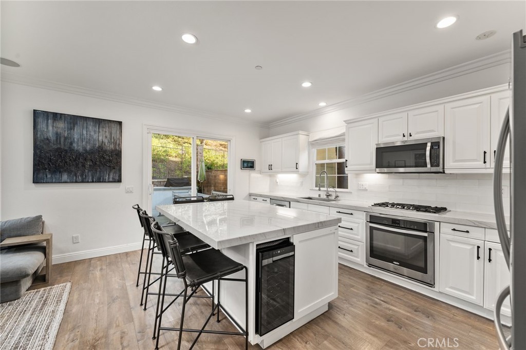10 Bower Tree Irvine, CA 92603 - Photo 7 of 37 a kitchen with stainless steel appliances granite countertop a stove a sink a microwave a refrigerator a dining table and chairs with wooden floor