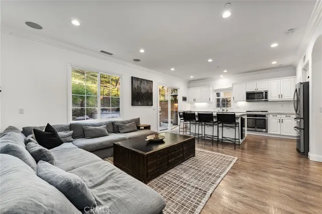 a living room with furniture kitchen view and a flat screen tv