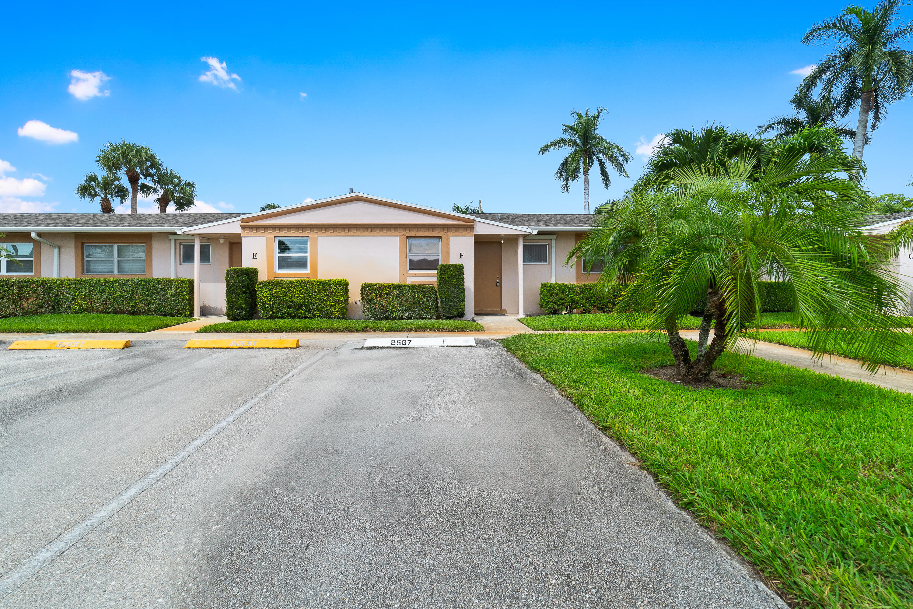 2567 Dudley Drive West, Unit F West Palm Beach, FL 33415 - Photo 2 of 41 a view of yellow house with a big yard and potted plants