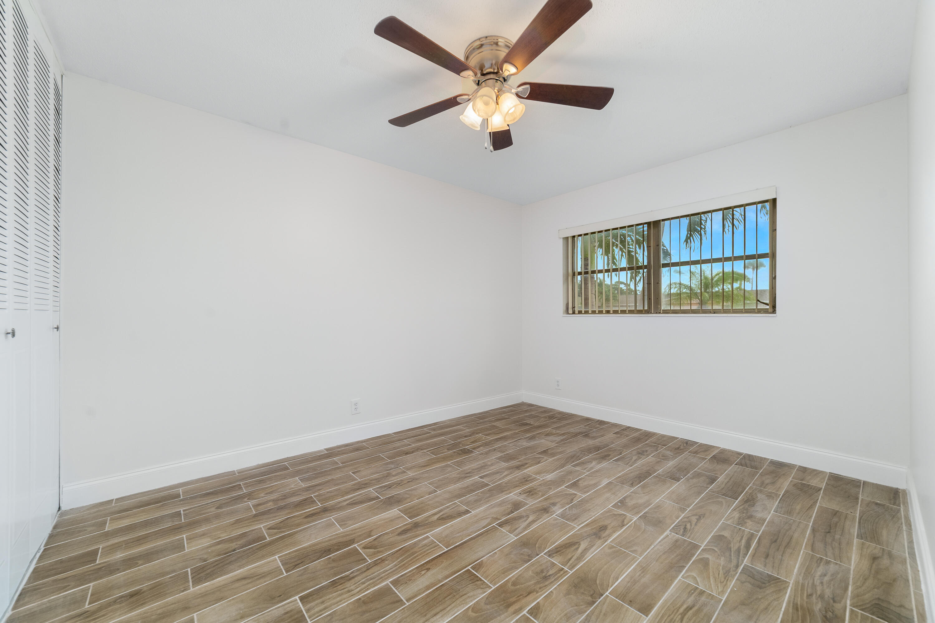 2567 Dudley Drive West, Unit F West Palm Beach, FL 33415 - Photo 23 of 41 an empty room with wooden floor and ceiling fan