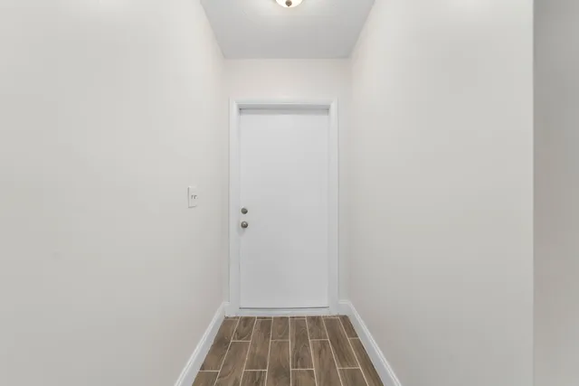 a view of a room with wooden floor and white door