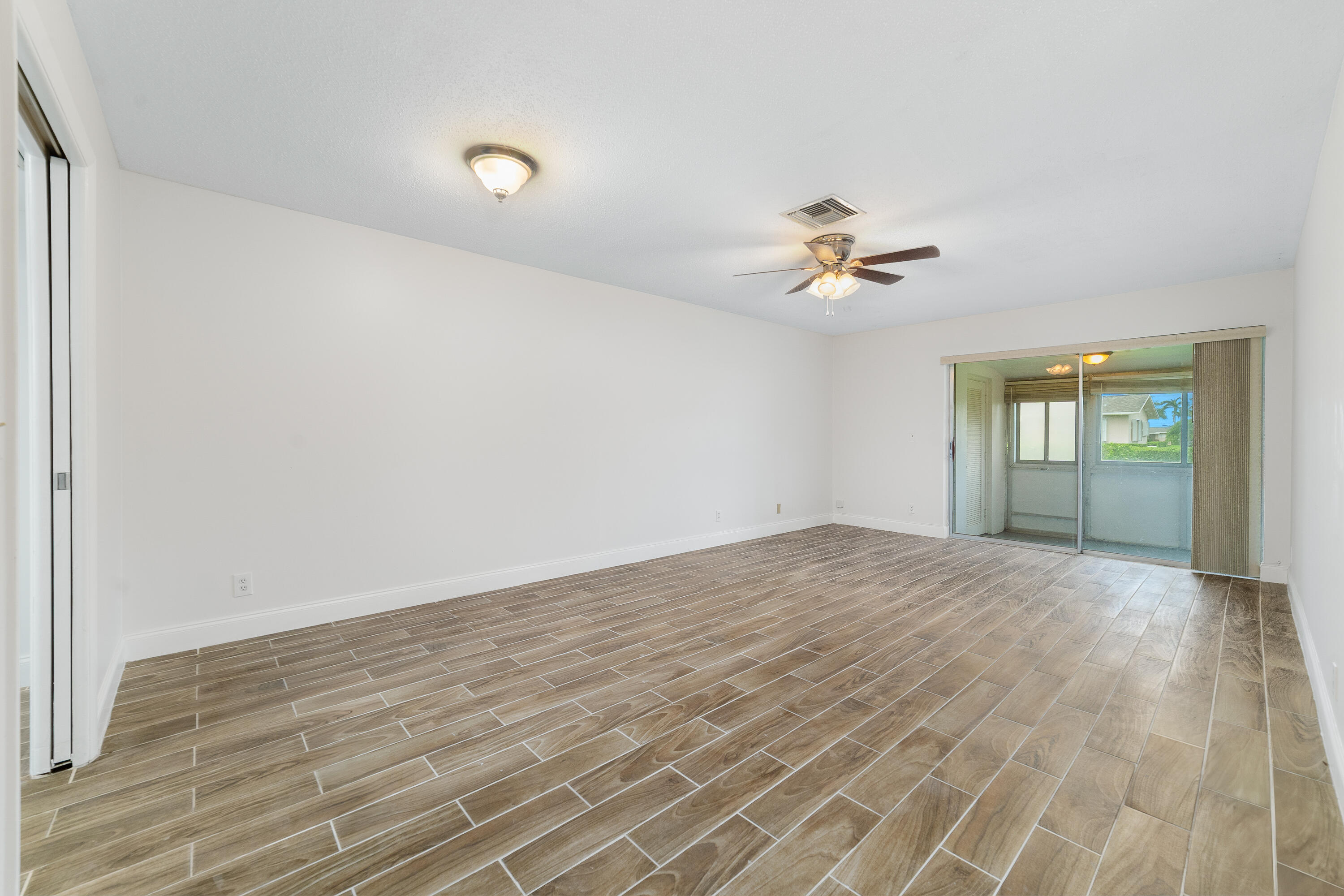 2567 Dudley Drive West, Unit F West Palm Beach, FL 33415 - Photo 7 of 41 wooden floor in an empty room with a window