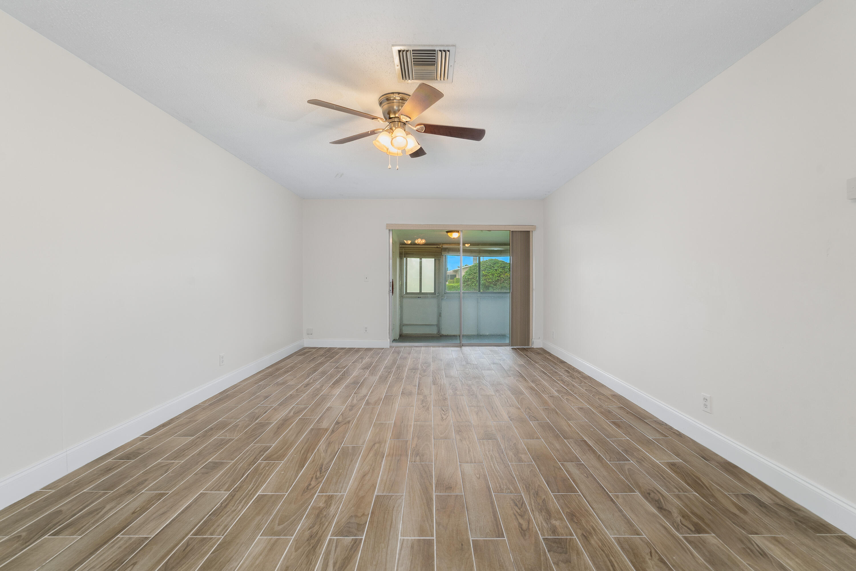 2567 Dudley Drive West, Unit F West Palm Beach, FL 33415 - Photo 9 of 41 wooden floor in an empty room with a window