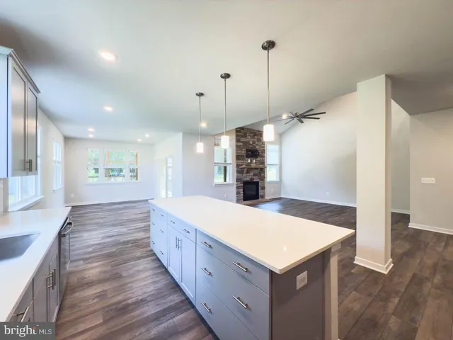 a large kitchen with kitchen island a refrigerator a stove a sink dishwasher and wooden cabinets with wooden floor