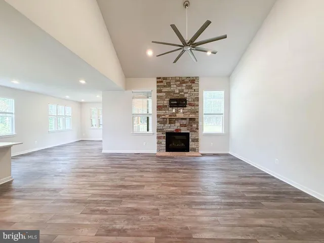 an empty room with wooden floor fireplace and windows
