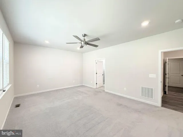 an empty room with a ceiling fan and window
