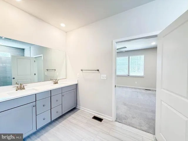 a spacious bathroom with a double vanity sink a large mirror and a shower