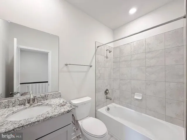 a bathroom with a granite countertop sink toilet mirror and bathtub