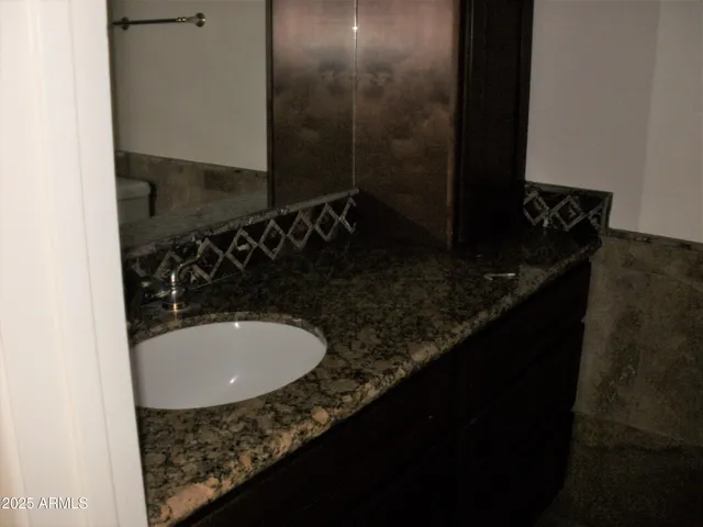 a bathroom with a granite countertop sink and a mirror