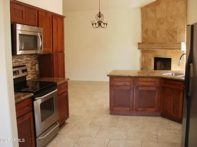 a kitchen with granite countertop a stove and a microwave with wooden cabinets