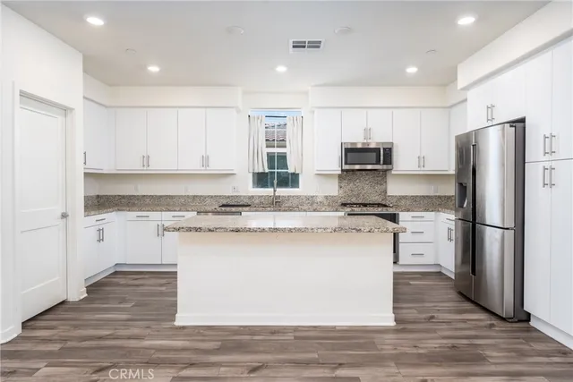 a kitchen with granite countertop a sink stainless steel appliances and white cabinets