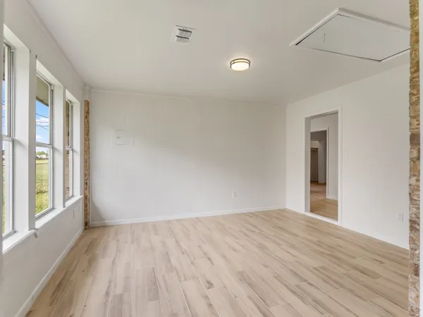 a view of an empty room with a window and wooden floor