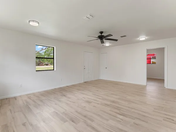 a view of an empty room with a ceiling fan and wooden floor