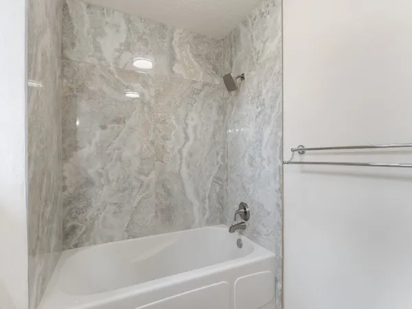a view of an empty room with wooden floor and a chandelier fan