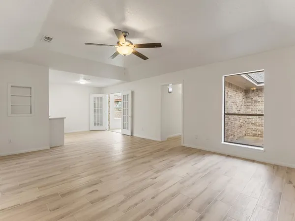 a view of an empty room with a window and wooden floor