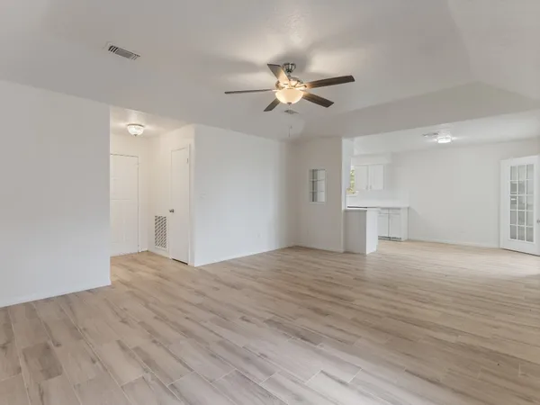 a view of empty room with wooden floor and ceiling fan