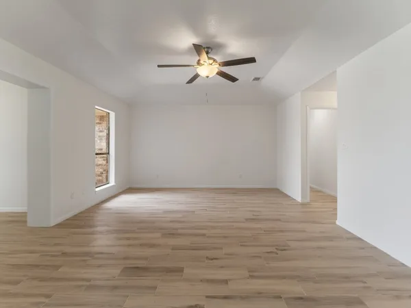 a view of empty room with wooden floor and fan
