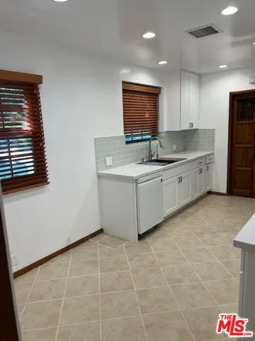 a large white kitchen with a sink and cabinets