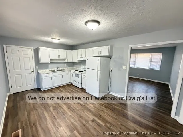 a kitchen with stainless steel appliances granite countertop a refrigerator a stove a sink dishwasher and white cabinets with wooden floor