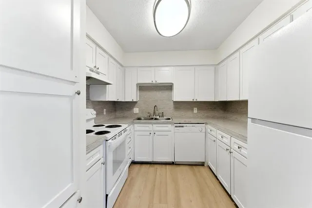 a kitchen with cabinets appliances a sink and a window