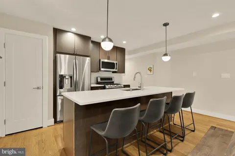 a kitchen with stainless steel appliances kitchen island a table chairs in it and wooden floors