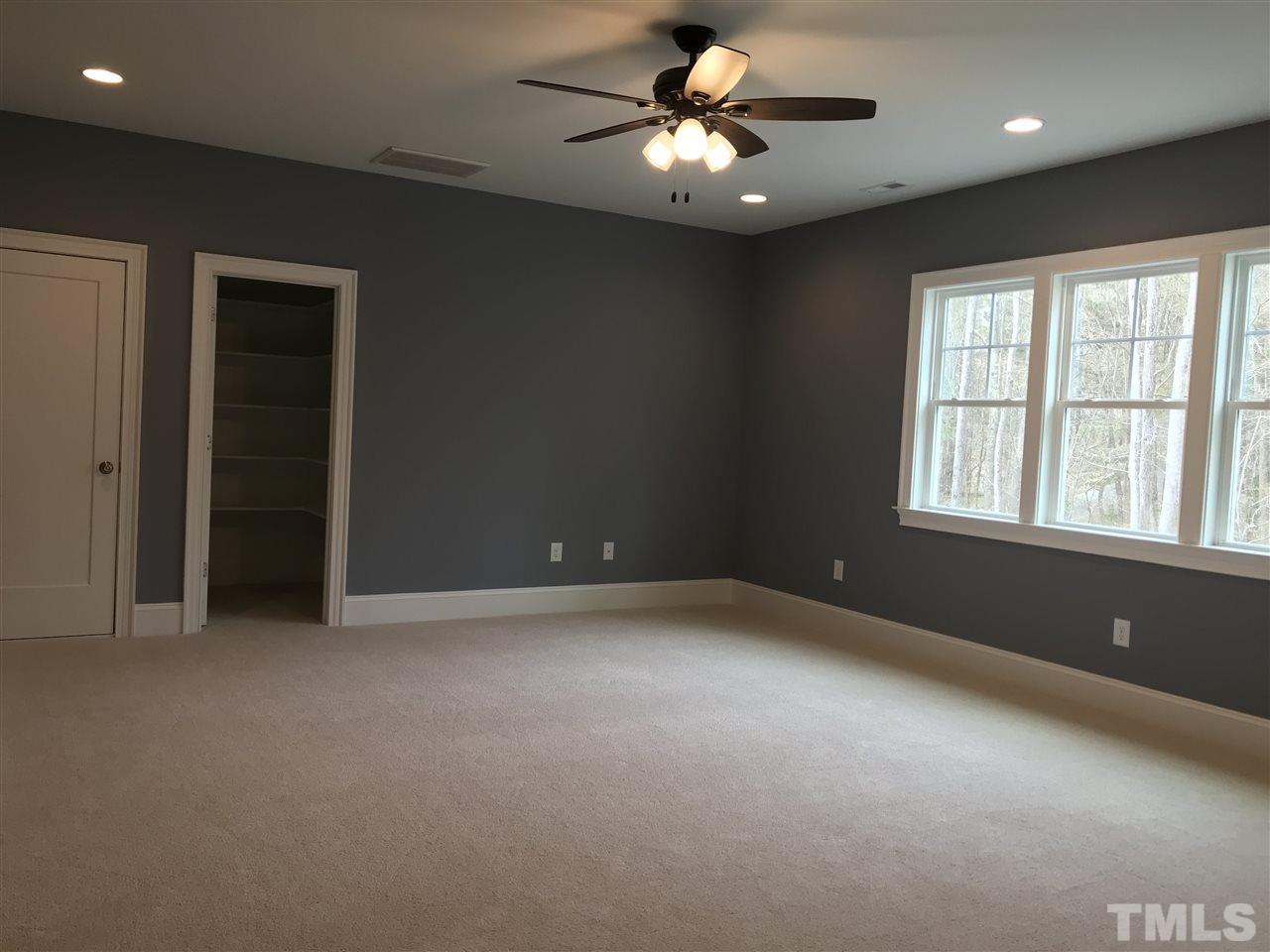 8707 Duckview Court Raleigh, NC 27613 - Photo 19 of 25 an empty room with a ceiling fan and windows