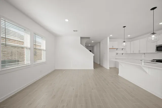 a view of kitchen with stainless steel appliances refrigerator oven stove and wooden floor