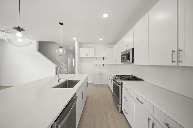 a kitchen with a sink a stove a refrigerator and white cabinets