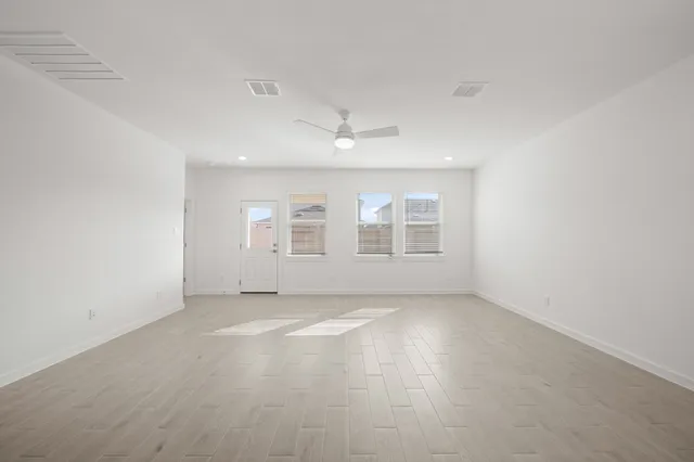 an empty room with windows and ceiling fan