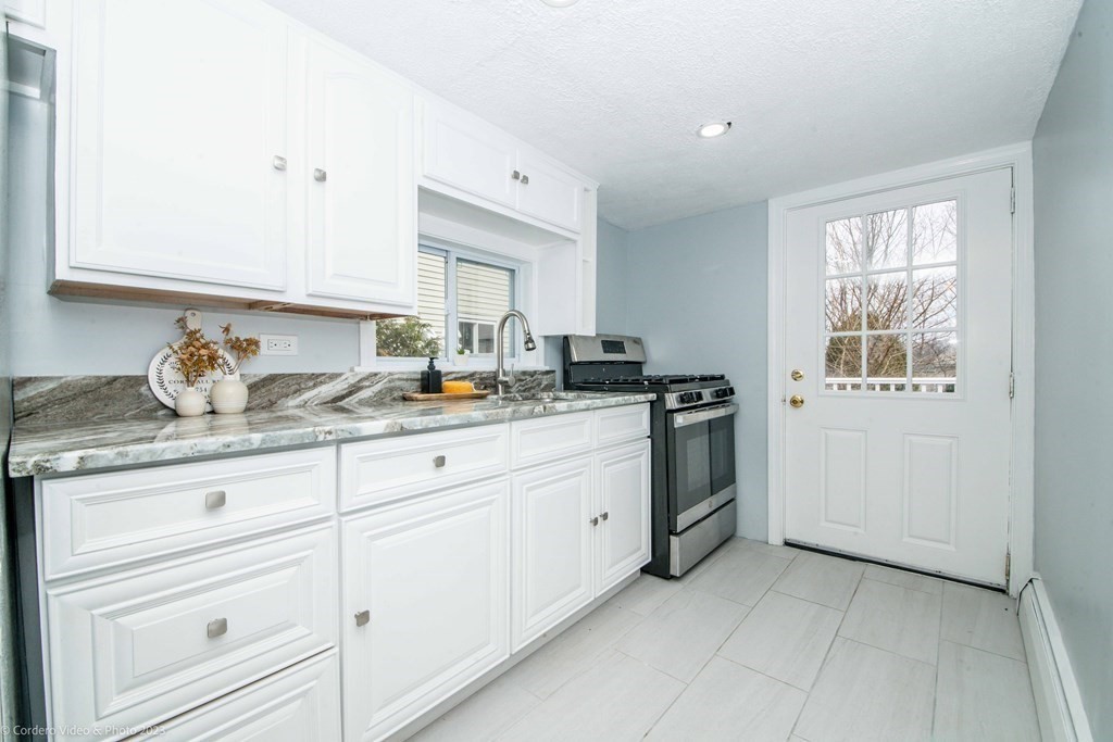 452 Tecumseh Street Fall River, MA 02721 - Photo 13 of 26 a kitchen with granite countertop white cabinets and white appliances