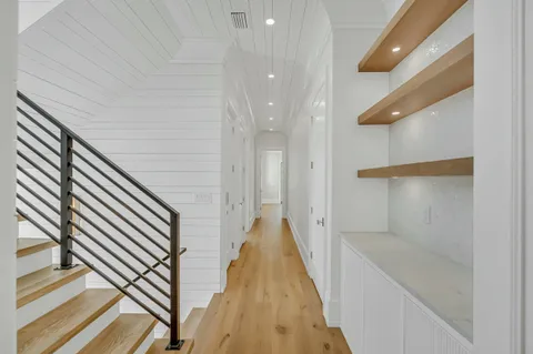 an empty room with wooden floor chandelier and windows