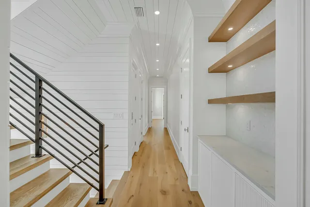 an empty room with wooden floor chandelier and windows