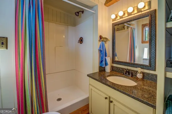 a bathroom with a sink a toilet a mirror and shower