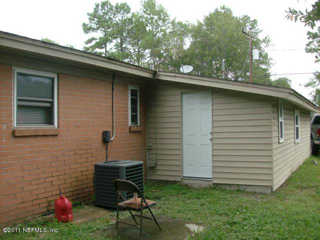 7344 Melvin Road Jacksonville, FL 32210 - Photo 10 of 11 a brick house with a bench in the patio