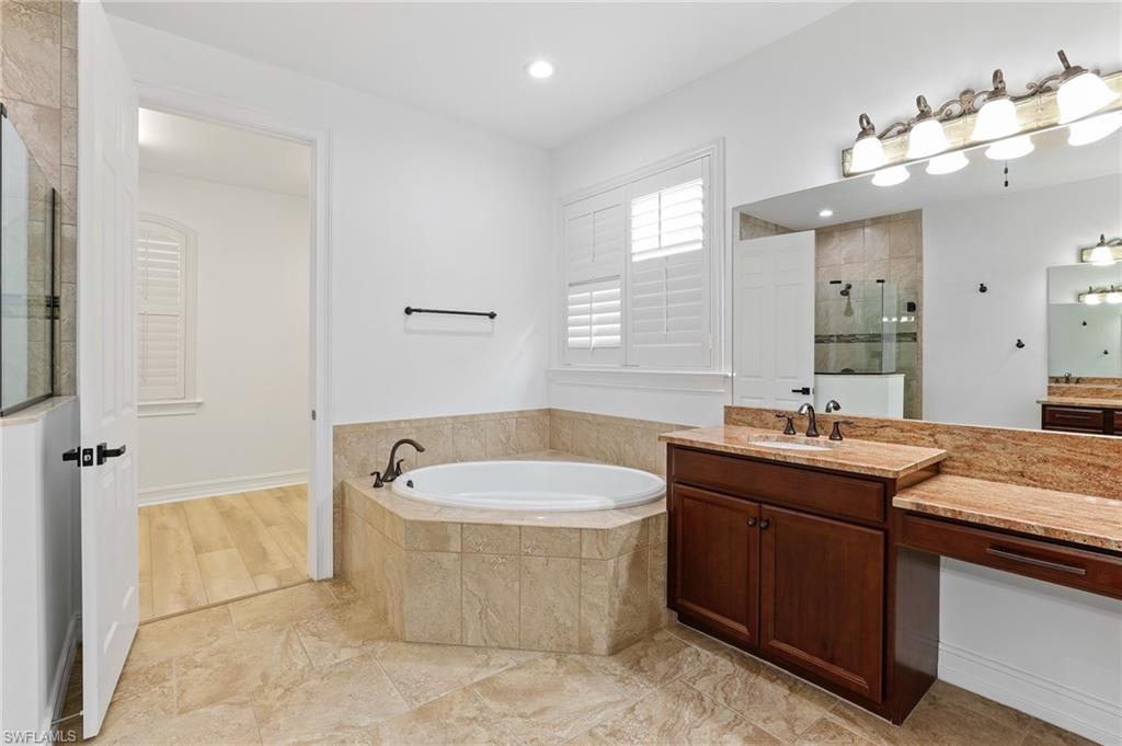 1584 Mockingbird Drive Naples, FL 34120 - Photo 22 of 40 a bathroom with a granite countertop sink a bathtub a mirror a vanity and bathtub