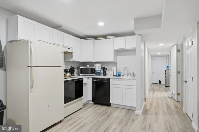 a kitchen with stainless steel appliances a refrigerator a sink and white cabinets
