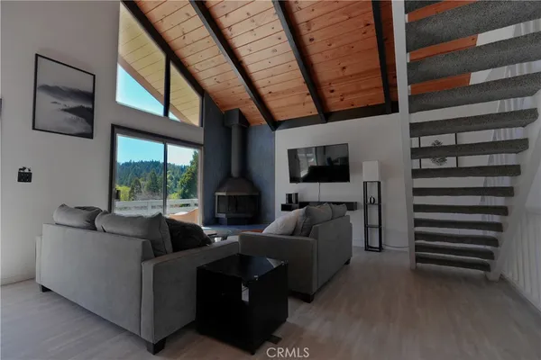 a living room with furniture a flat screen tv and a floor to ceiling window