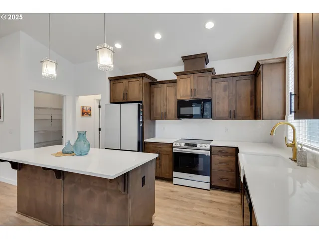 a kitchen with stainless steel appliances kitchen island granite countertop a refrigerator a stove a microwave a sink and a dining table