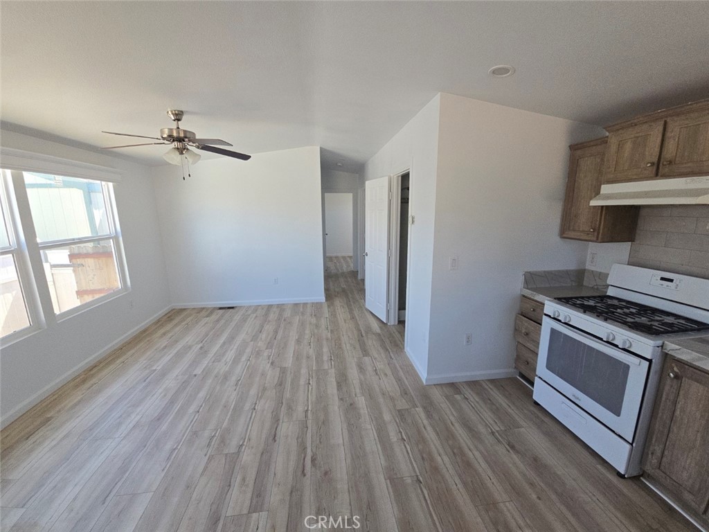 13096 Blackbird Street, Unit 164 Garden Grove, CA 92843 - Photo 2 of 19 an empty room with wooden floor a ceiling fan and windows