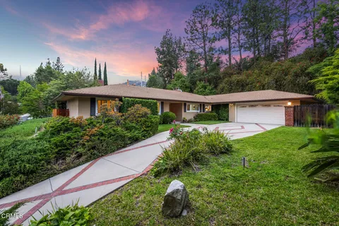a view of a house next to a yard with plants and trees