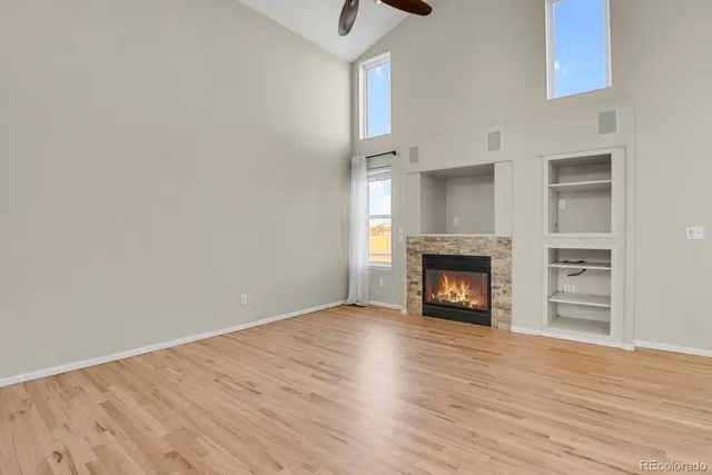 a view of an empty room with wooden floor fireplace and a window