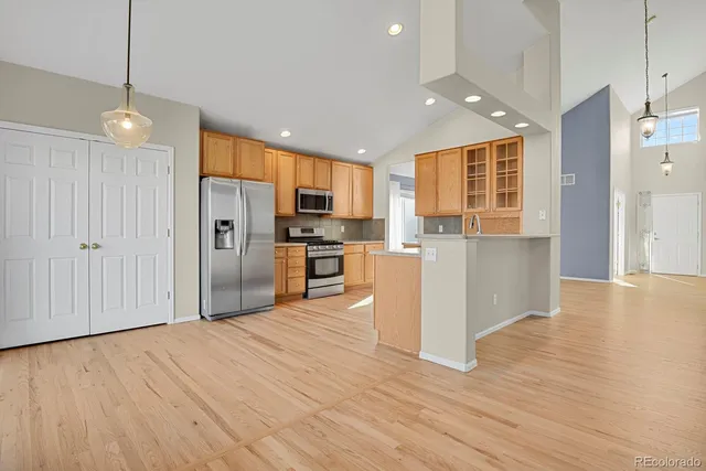 a kitchen with stainless steel appliances granite countertop a refrigerator a stove oven a sink dishwasher and wooden cabinets with wooden floor