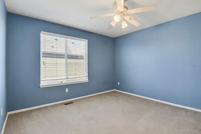 an empty room with a window and a fan