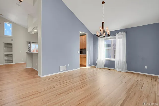 a view of a livingroom with a chandelier fan and windows