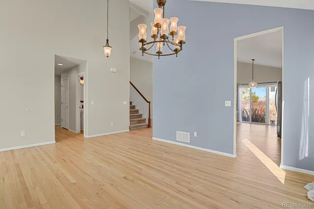a view of an empty room with wooden floor and a chandelier